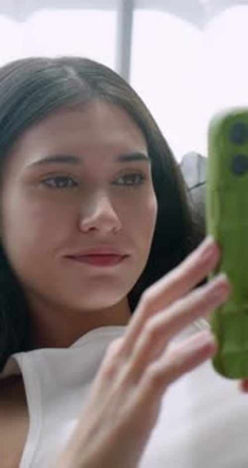 Vertical clip. Close up of young woman using smart phone on sofa at home.