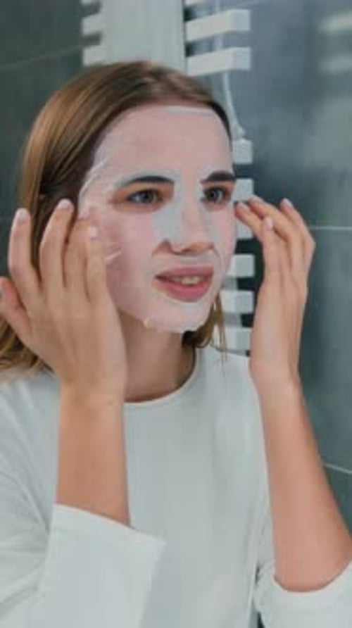 Woman Applying Sheet Face Mask in Bathroom