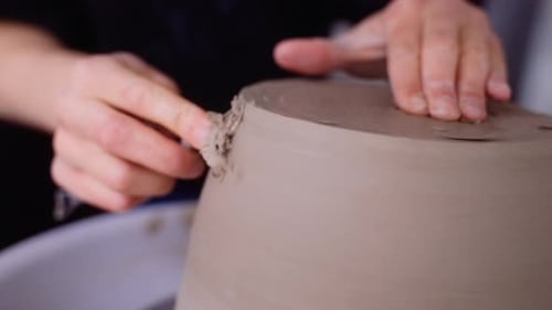 Un potier rase la poterie sur une roue à poterie