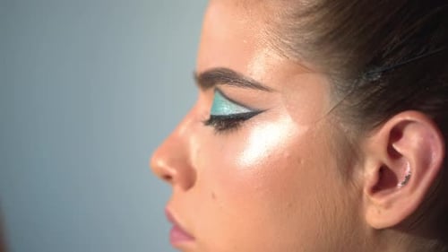 Visagistin trägt kosmetisches Gesicht auf, Hand des Make-up-Meisters, die Lippen junger Schönheit zu malen