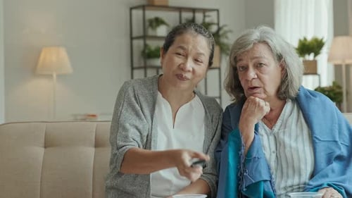 Two Women Friends Smiling on Couch Watching TV