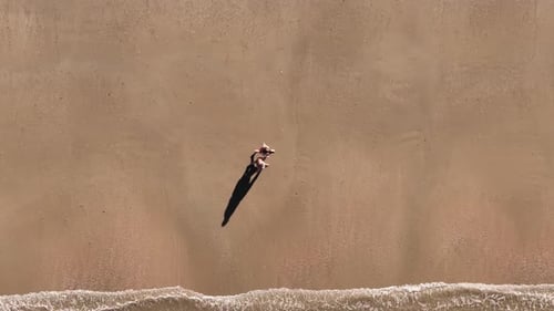 Aerial View of Woman Walking on Sandy Beach