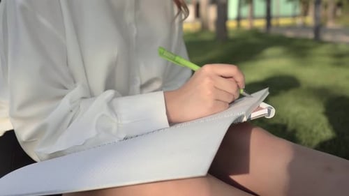 Young Adult Writing in Notebook Outdoors