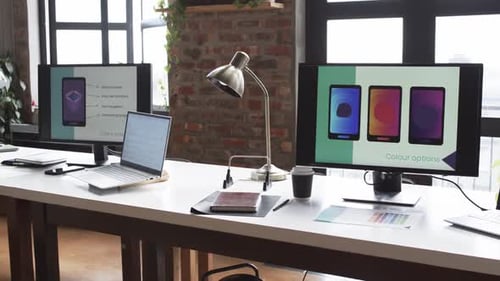 A desk with multiple computer screens displaying app design
