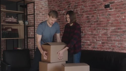 Young Couple Packing Cardboard Boxes in Cozy Home