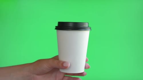 Hand Holds Coffee Cup Against Green Screen