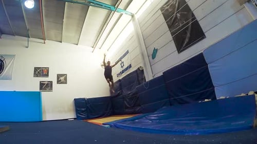 Man Doing Gymnastics Moves Indoors on Trampoline