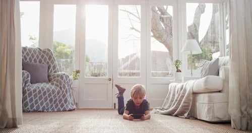 Young Boy Using Phone on Floor in Bright Room