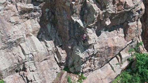 Climber Ascending Steep Rock Face Using Rope