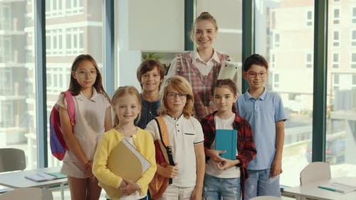 Teacher and School Children Standing Together in the Middle of the Classroom