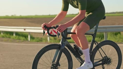 Cyclist Rides Bike on Rural Road in Daylight
