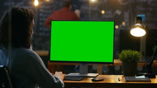 Beautiful Female Office Employee at Her Desktop Works on a Mock-up Green Screen Personal Computer.