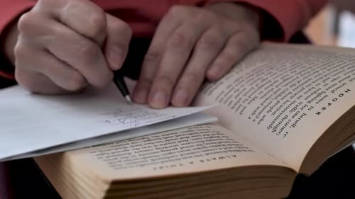 Ein Student liest ein Buch und macht sich Notizen mit einem Stift. Lerne Englisch. Die Hand der Frau hält