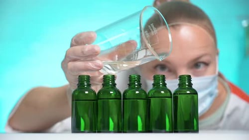 Pouring Liquid into Green Glass Bottles in Lab