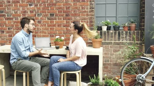 4k video footage of a young couple sitting outside a cafe and having an argument