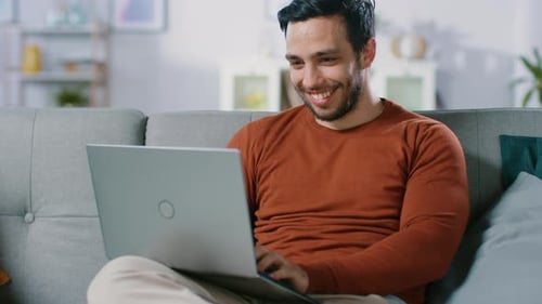 Man Relaxing On Couch Using Laptop Computer