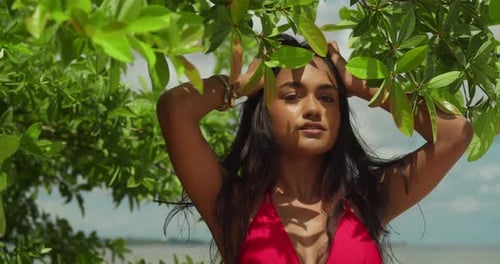 An Indian girl in a vibrant red bikini facial close up savors the beauty of a Caribbean tropical bea