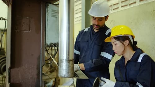 Factory Workers Inspect Machine with Laptop in Workplace
