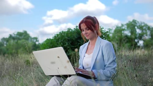 Telecommuting Office Worker Charming Female Freelancer Working at the Computer Sitting on Clearing
