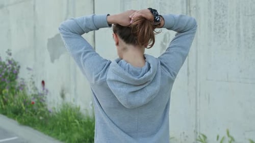 Woman Puts Her Hair Up into a Ponytail