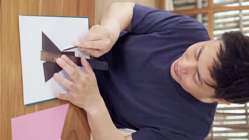 Man Cutting Black Paper with Blade and Ruler