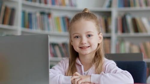 Young Girl Smiles and Gives Thumbs Up in Library