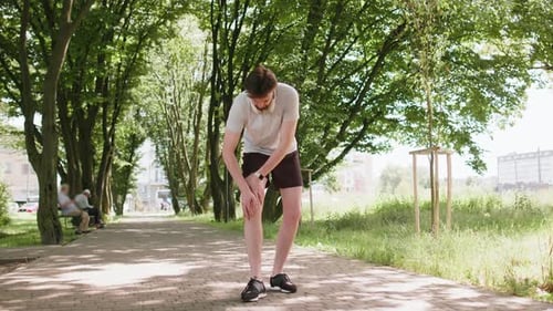 Runner Athlete Man with Muscle Leg Pain Trauma Injury While Jogging Cramp Calf Sport in City Park