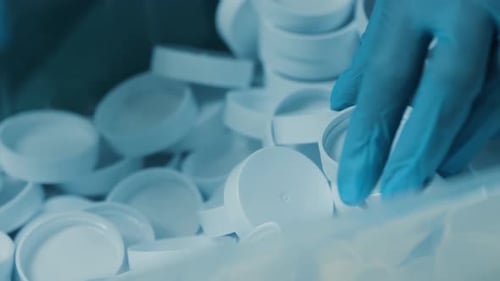 Gloved Hands Sorting White Plastic Lids
