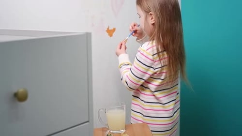 Young Girl Painting Orange Color on a White Wall