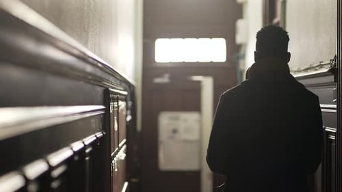 Person walking down corridor about to leave home apartment, step out in city