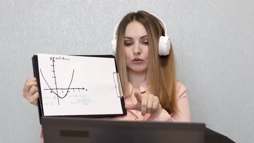 A math teacher conducts an online lesson with high school students via a laptop.