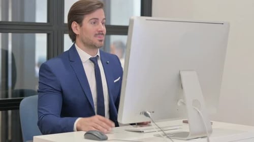 Man in Suit Talking to Computer in Office