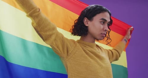 Young Adult Holding LGBTQ Pride Flag Indoors