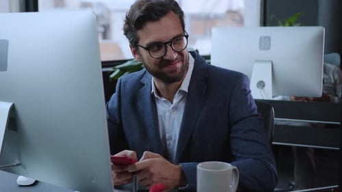 A Businessman is Diligently Working at His Desk Using a Smartphone in a Modern Office Setting