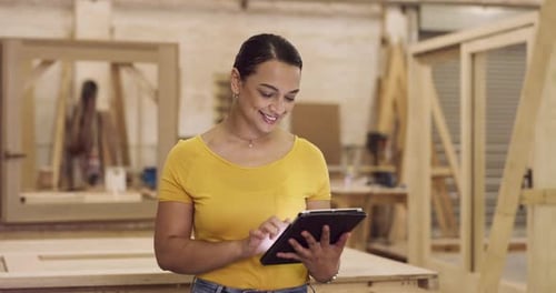 4k video footage of a young businesswoman in her carpentry workshop using her digital tablet