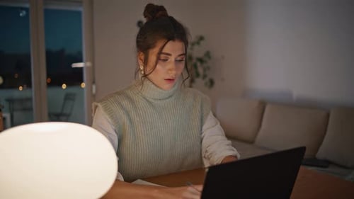 Woman Working at Laptop in Home at Night