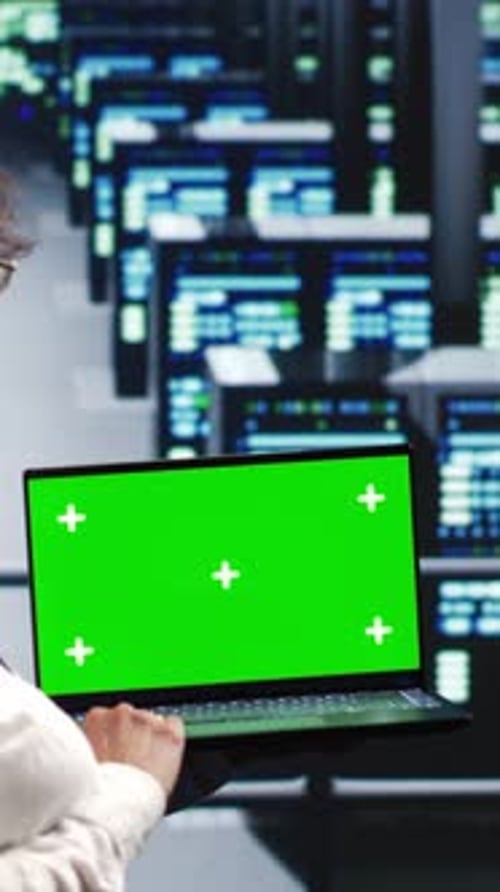 Adult Holding Laptop with Green Screen in Server Room