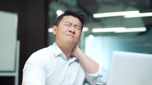Man Massaging Neck in Office at Work
