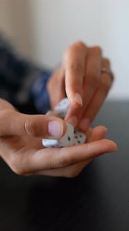 Hands Playing Dice Game on Black Table