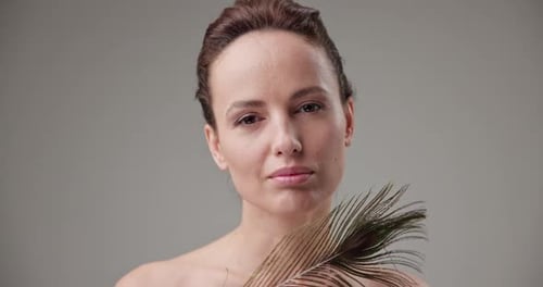 Woman Posing with a Peacock Feather in Studio