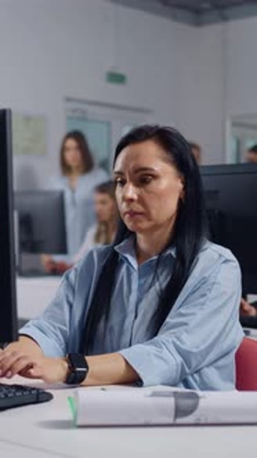 Focused Middle Aged Woman Working at Computer in Modern Open Plan Office Typing on Keyboard and