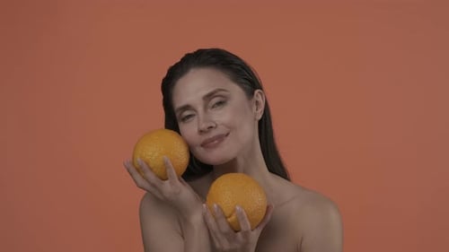 Woman Poses with Oranges on Orange Background