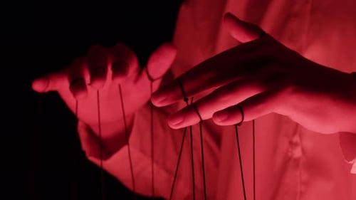 The Puppeteer Controls the Puppets in the Theater in Red Neon Light Closeup Managing People at Work