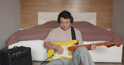 Man Playing Electric Guitar in Bedroom