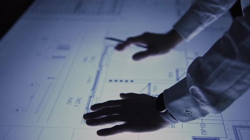 Architect Inspecting Blueprints on Illuminated Table