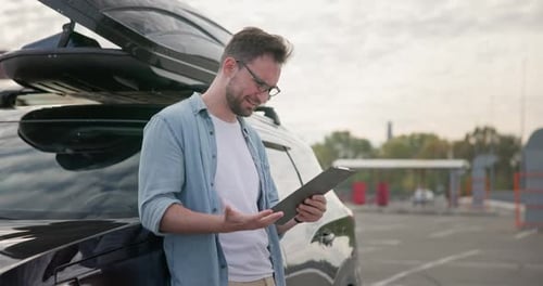 A Sad Angry Man Stands Near By a Car and Looks at the Bills or Checks Issued to Him