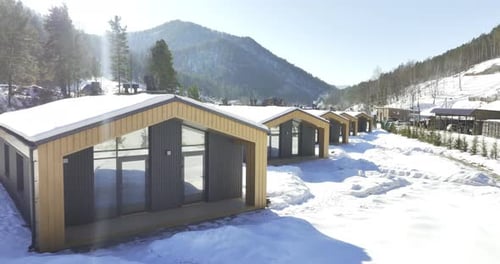 Cottages Painted in Golden Brown Stand Among Snowy Mountains