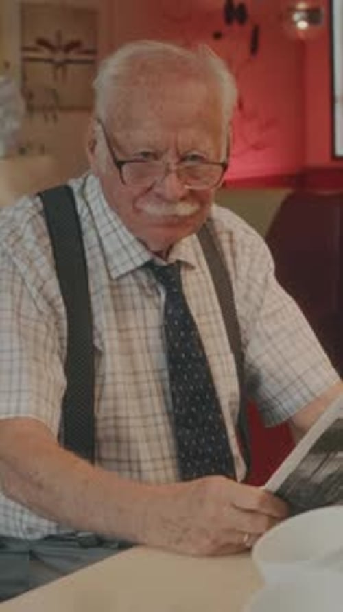 Vertical Portrait of Senior Man with Newspaper in 1980s Style Diner