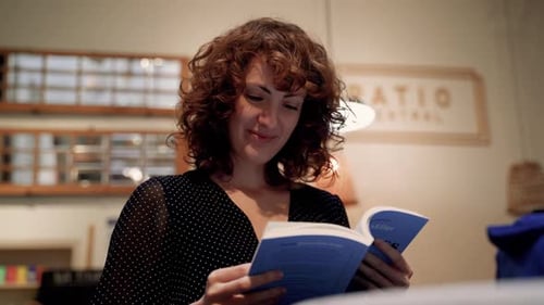 Pretty Young Curly Woman Commenting And Laughing At Book Reading