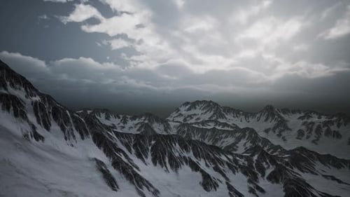 Aerial Flyover of Majestic Snow Mountains Under Dramatic Clouds